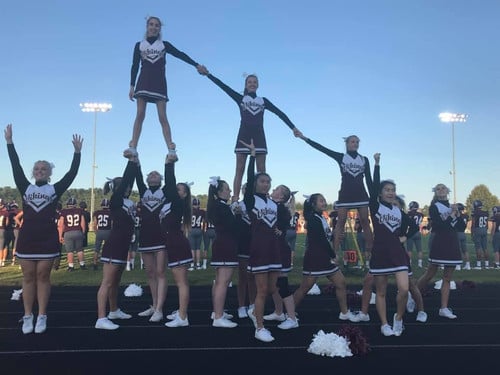 The cheerleaders completing a pyramid with an extension, elevator, and thigh stand all connected together with the flyers holding hands